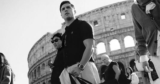 Man wearing black THEODORE polo shirt walking past the Colosseum in Rome, capturing modern luxury style in a timeless setting