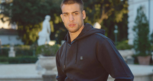 Man wearing a Navy THEODORE hoodie and tailored trousers in an outdoor estate setting, showcasing refined casual menswear and modern individuality.